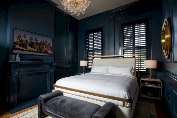 A stylish bedroom with dark walls, a white bed, a bench, two lamps, a TV, and a decorative chandelier, creating a cozy atmosphere.