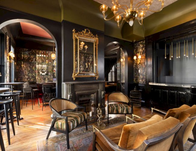 A stylish interior with vintage decor, featuring elegant furniture, a fireplace, and ornate lighting, creating a cozy atmosphere.