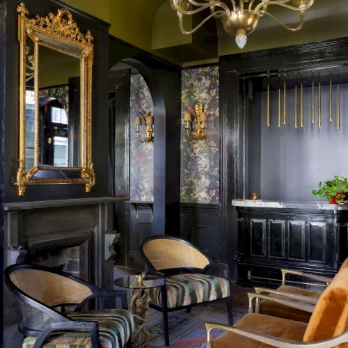 A luxurious room with elegant chairs, a chandelier, ornate mirror, and richly decorated walls, exuding a classic and sophisticated vibe.