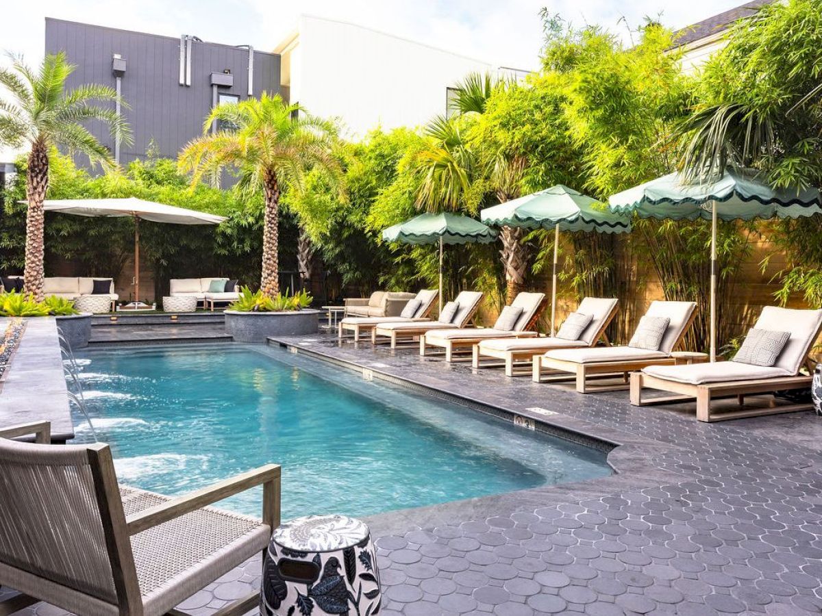 An inviting poolside scene with lounge chairs, umbrellas, and lush greenery on a sunny day.